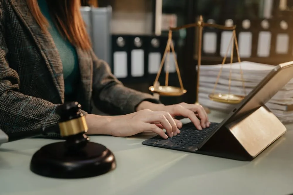 Woman sitting in front of a tablet writing down legal notes