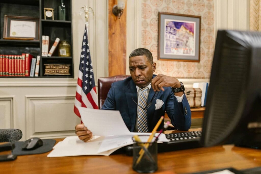 Man sitting with his desk reading from a paper.