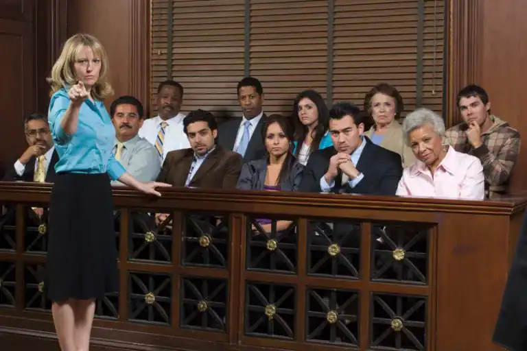 Attorney addressing a jury in a courtroom while pointing forward, with a diverse group of jurors seated attentively behind the jury box.