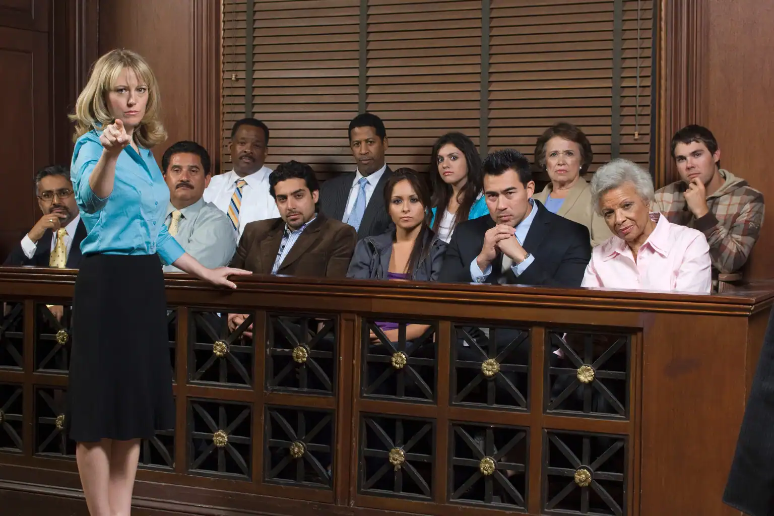 Attorney addressing a jury in a courtroom while pointing forward, with a diverse group of jurors seated attentively behind the jury box.